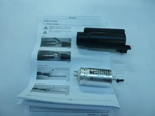 Zwei Bauteile, darunter ein Kondensator und ein schwarzes Gehäuse, liegen neben einer Anleitung. Das Produkt gehört zur Marke Remeha.